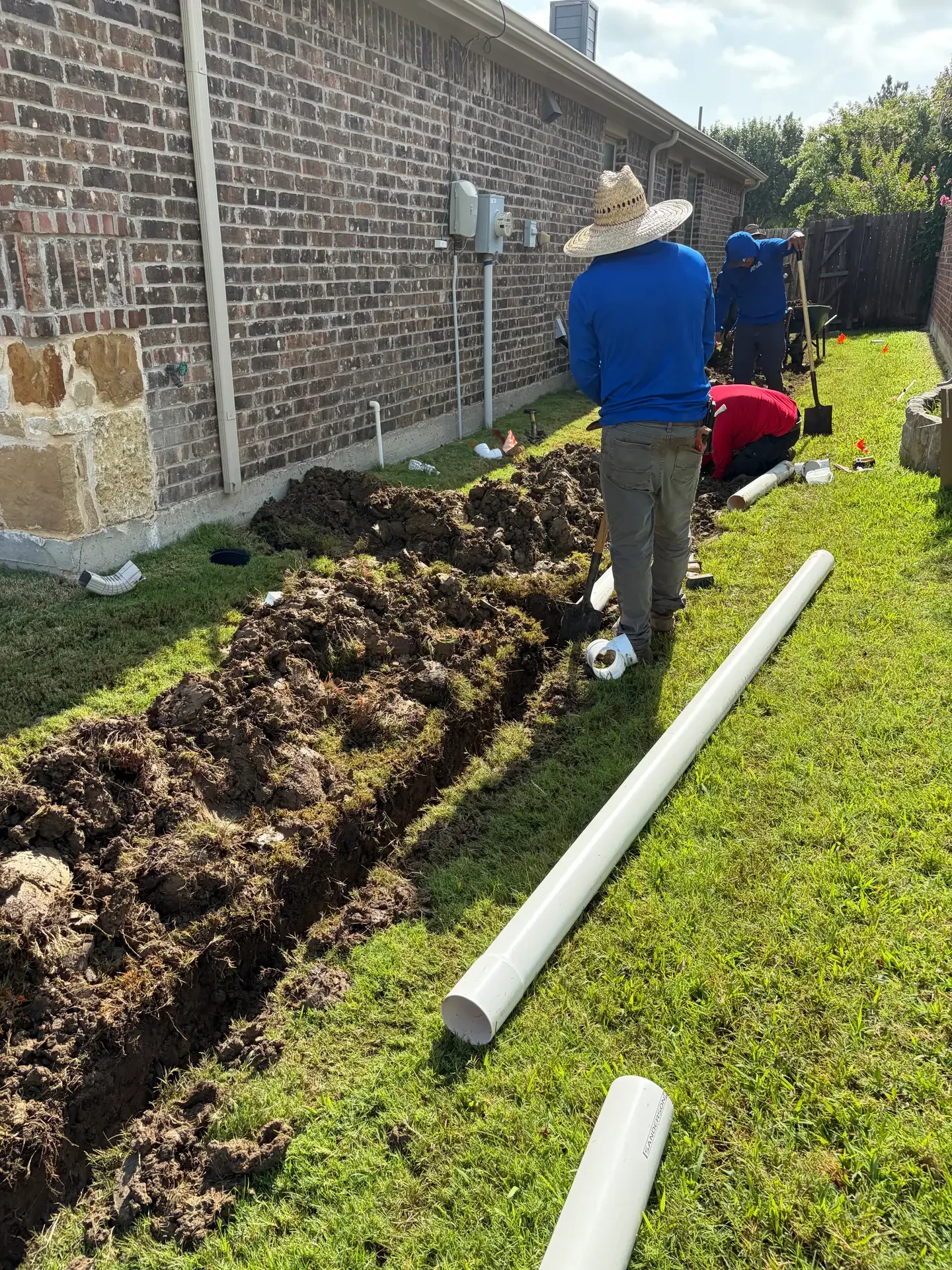 crew trenching beside brick foundation