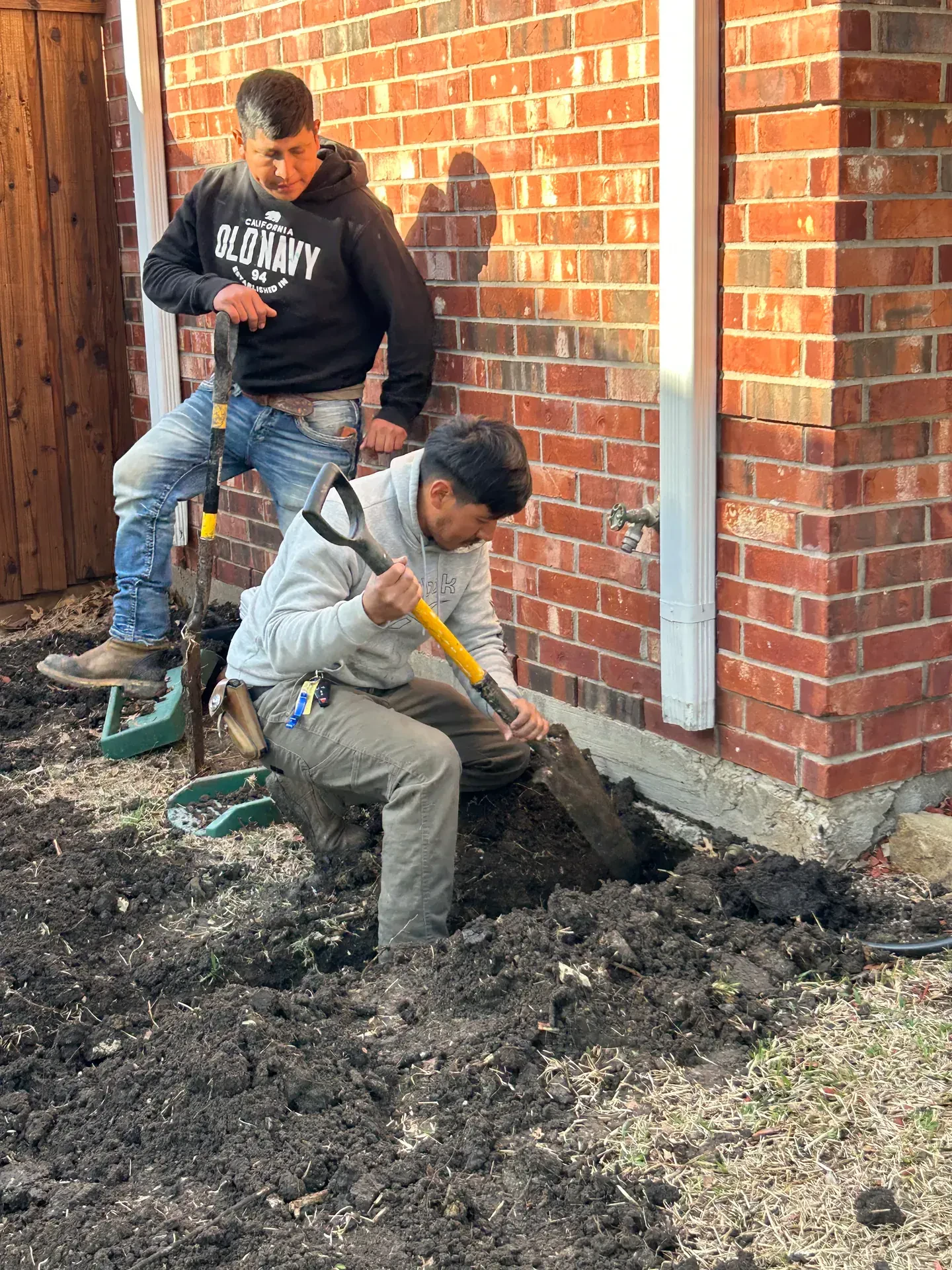 close view of crew digging beside downspout