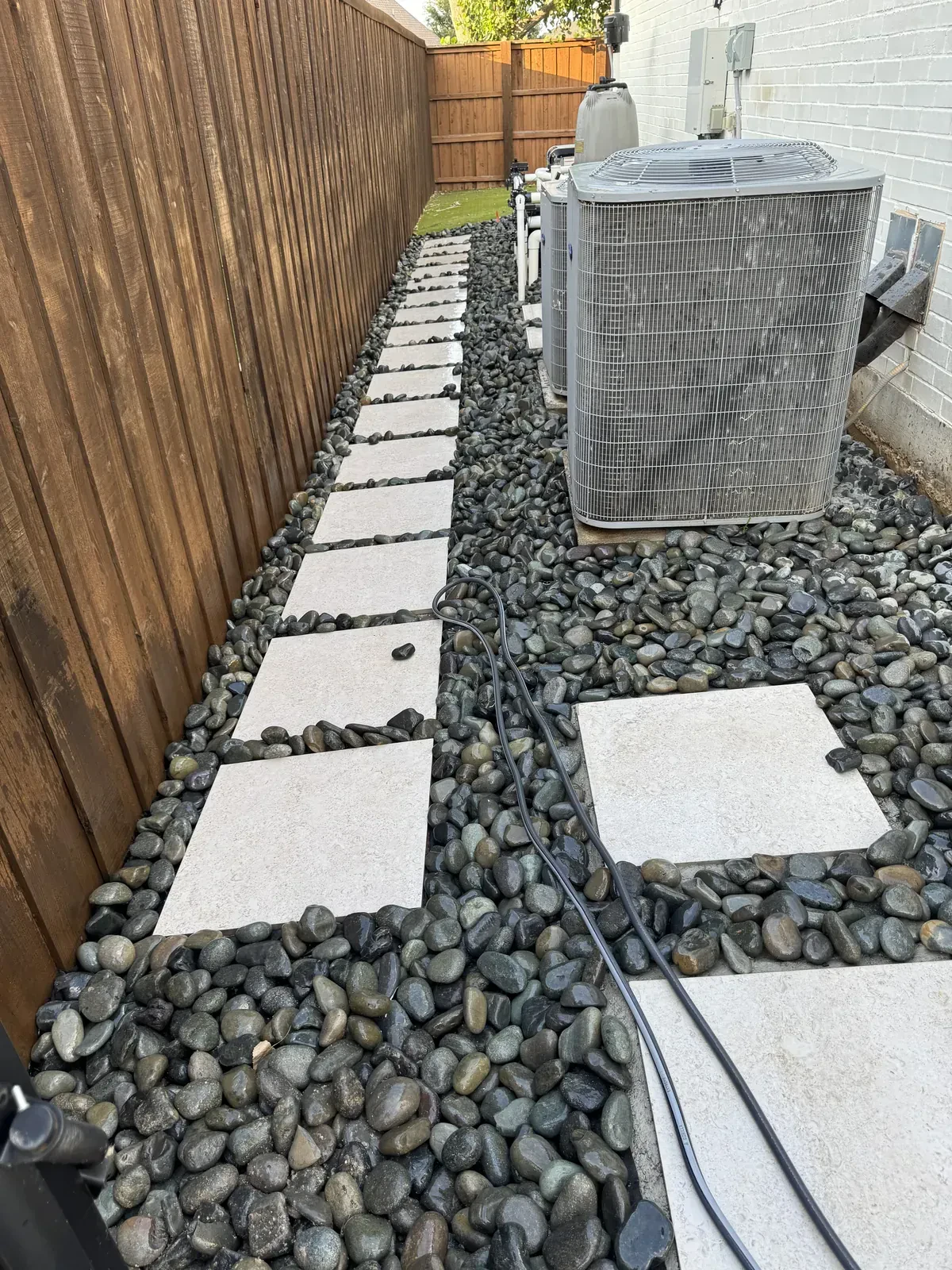 Stepping stones and river rock beside air conditioners