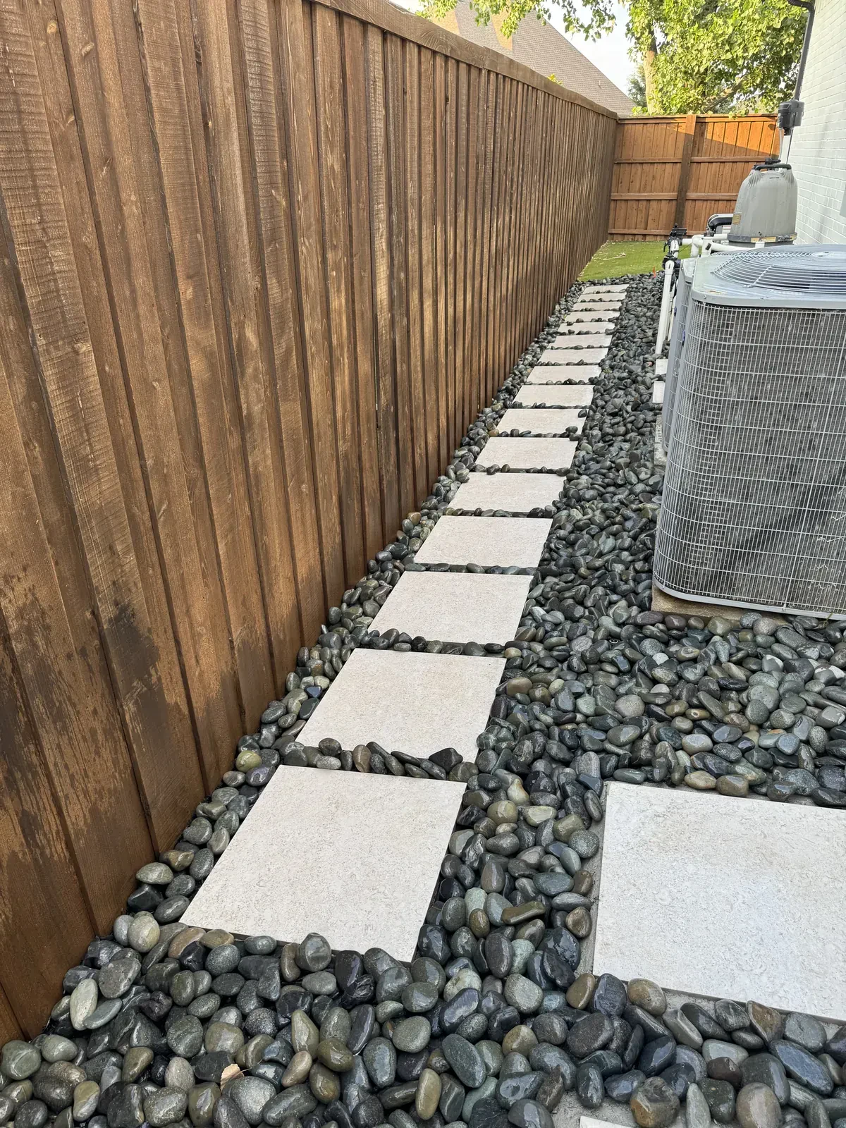 Finished river rock walkway along fence