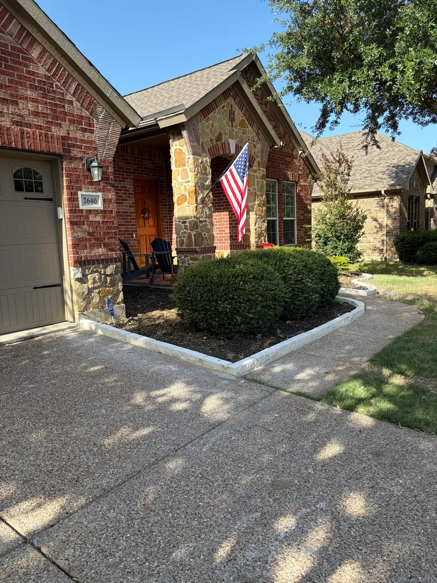 Finished white stone edging around a planted front entry bed