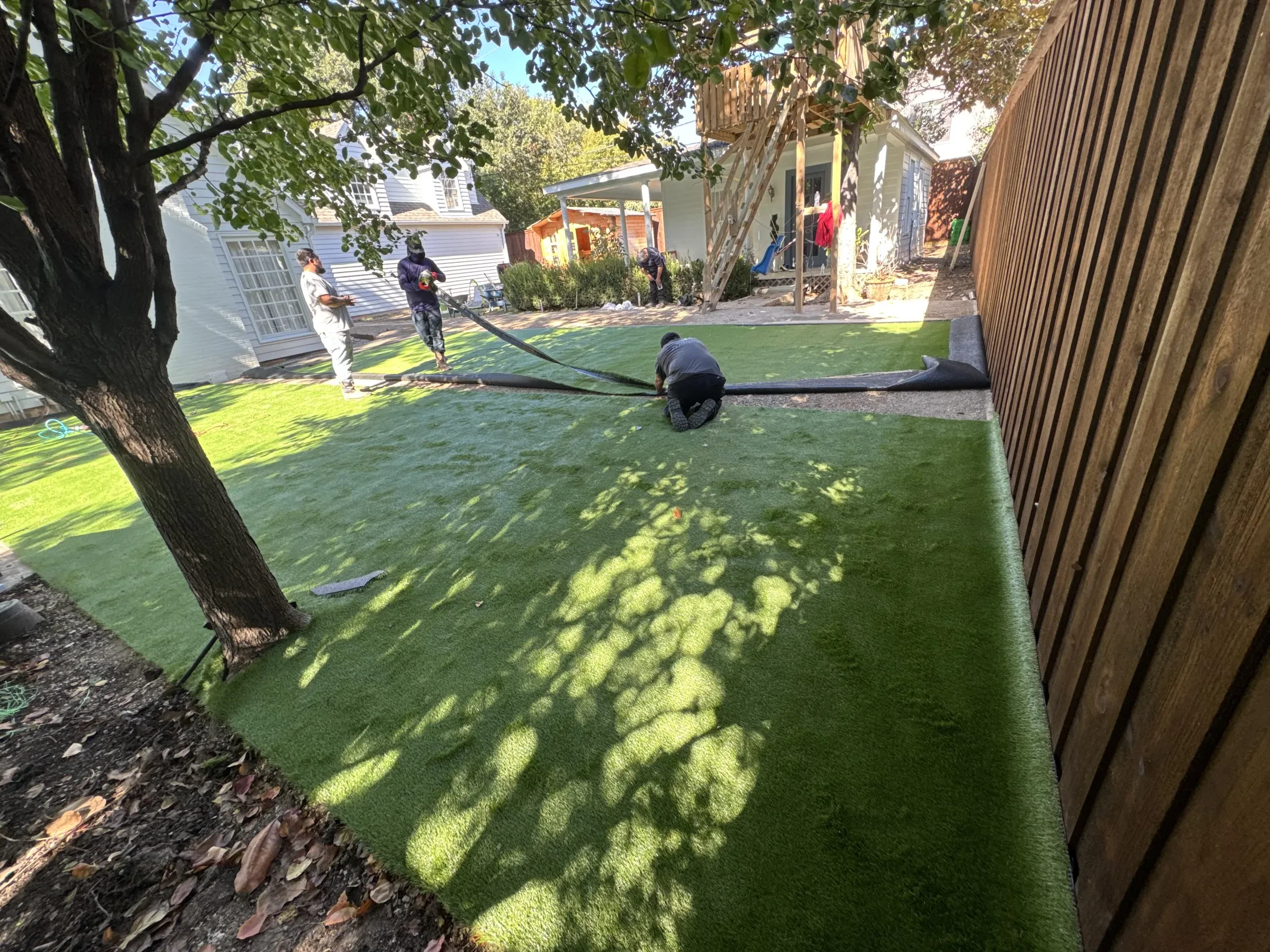 Artificial turf being laid and secured in a residential yard